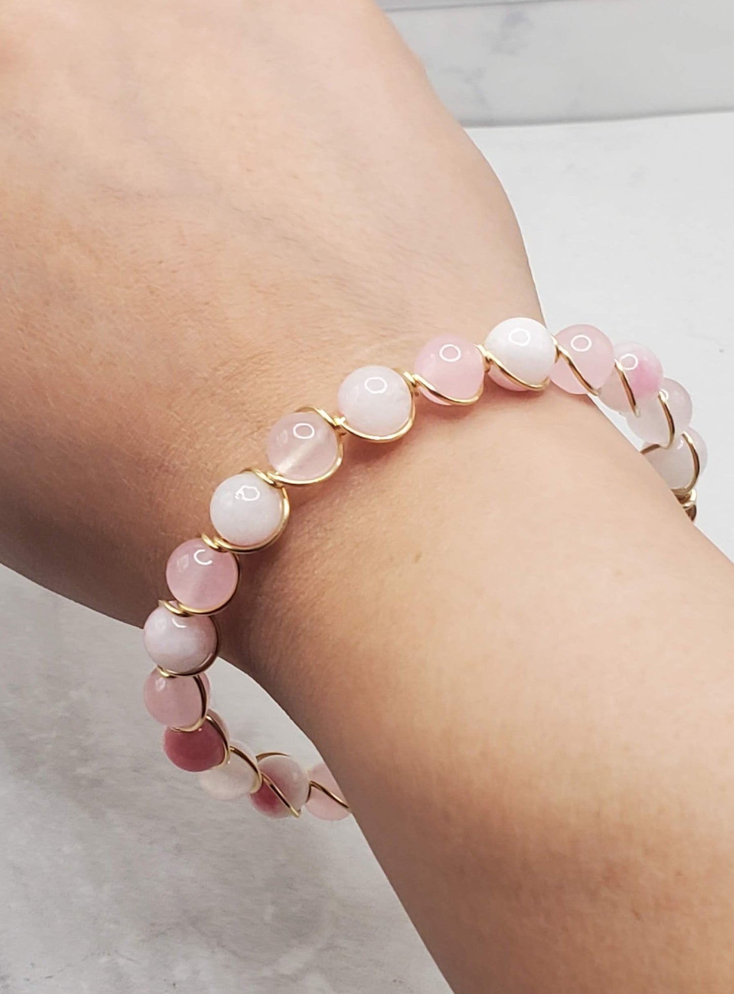 Pink gemstone bracelet | Gold bangle bracelet on a wrist | Braceliss
