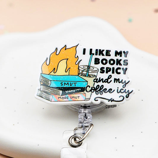 Retractable badge holder with a design of flaming books and iced coffee, featuring the phrase “I Like My Books Spicy and My Coffee Icy,” perfect for book lovers and healthcare workers.