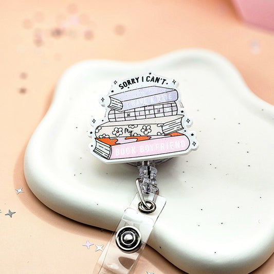 Retractable badge holder with a pastel book stack design and the phrase “Sorry I Can’t I Have A Date With My Book Boyfriend,” perfect for book lovers, teachers, and healthcare workers.