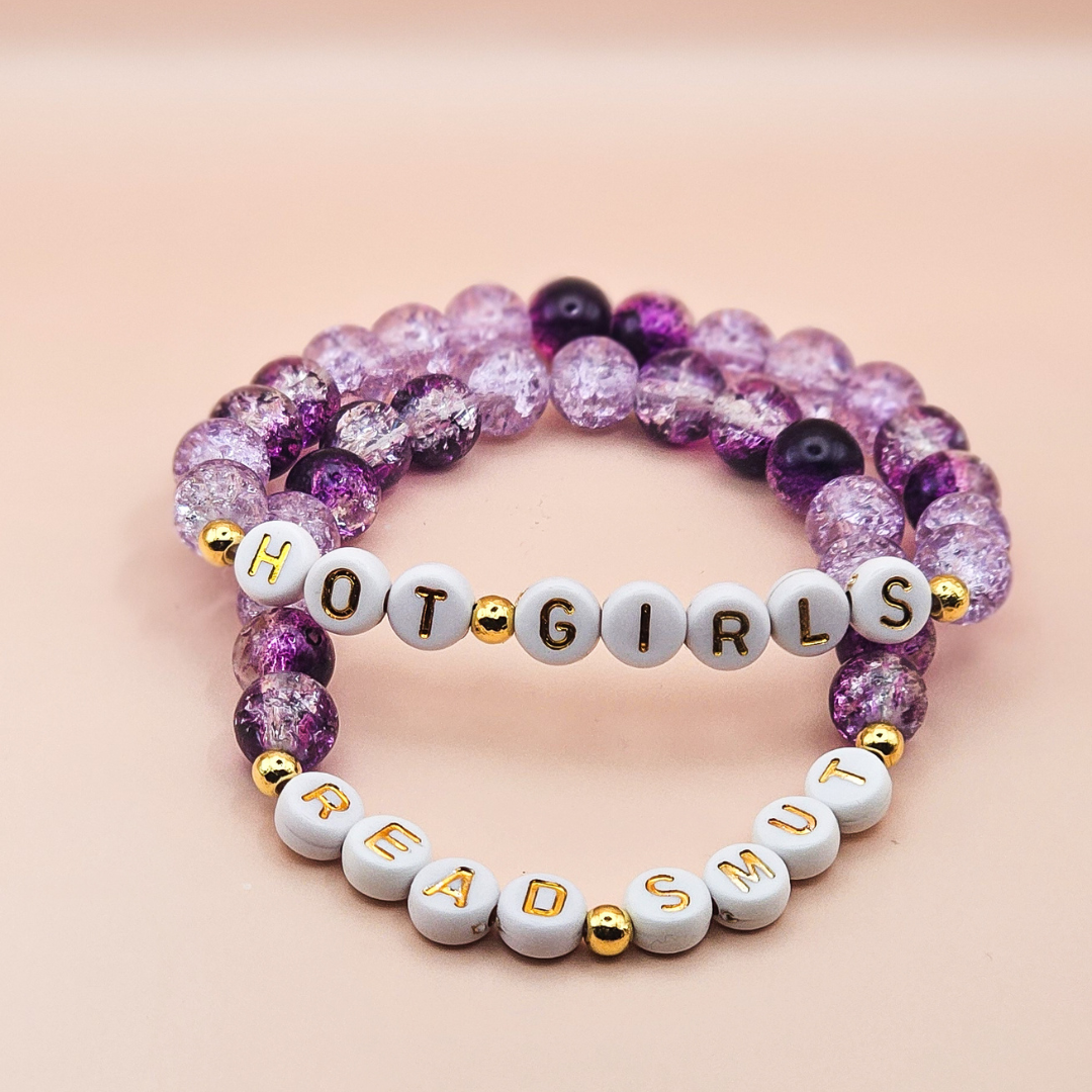 Bracelet with letter beads spelling 'HOT GIRLS READ SUIT' on a pink background