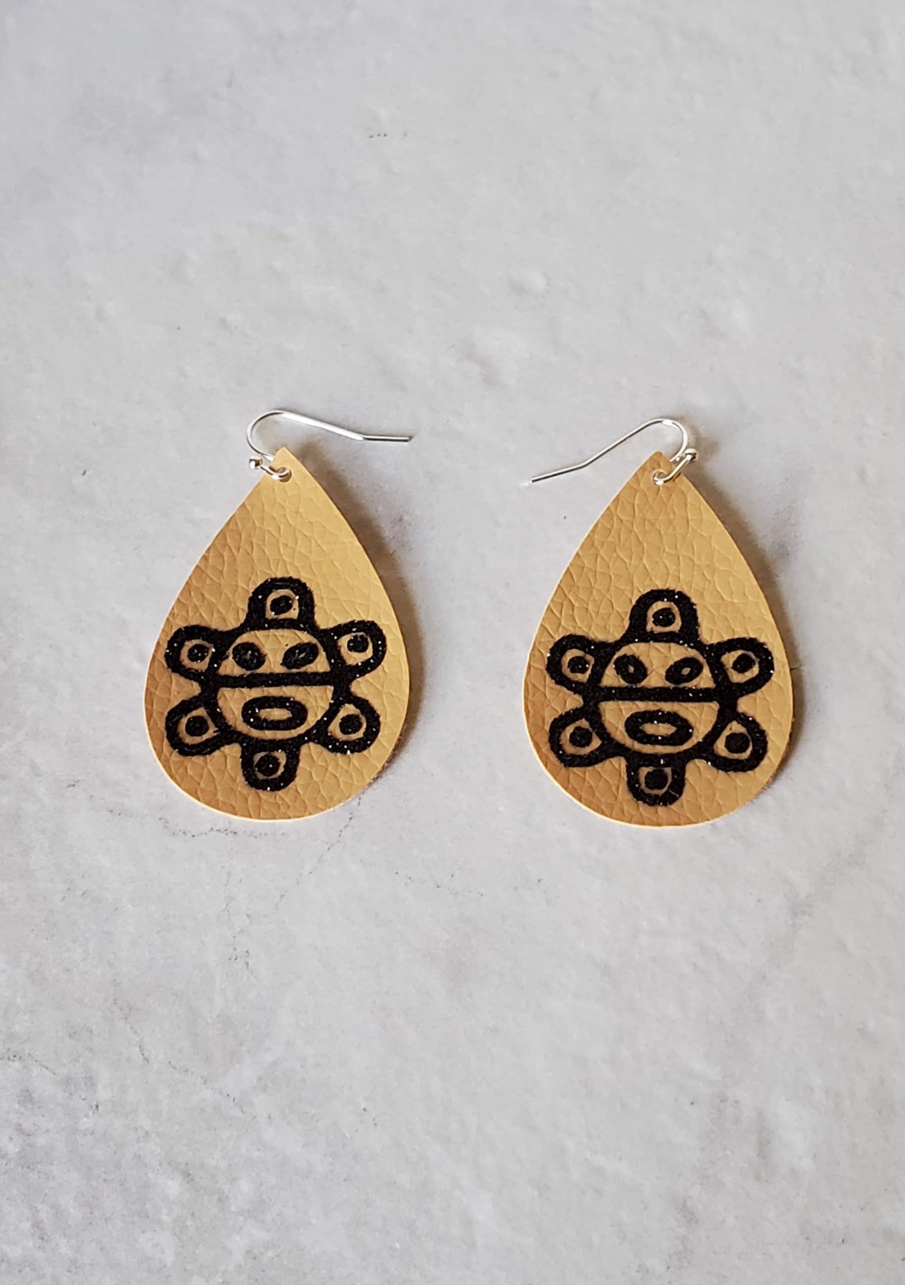 Taino sol earrings - brown faux leather earrings laying flat - braceliss