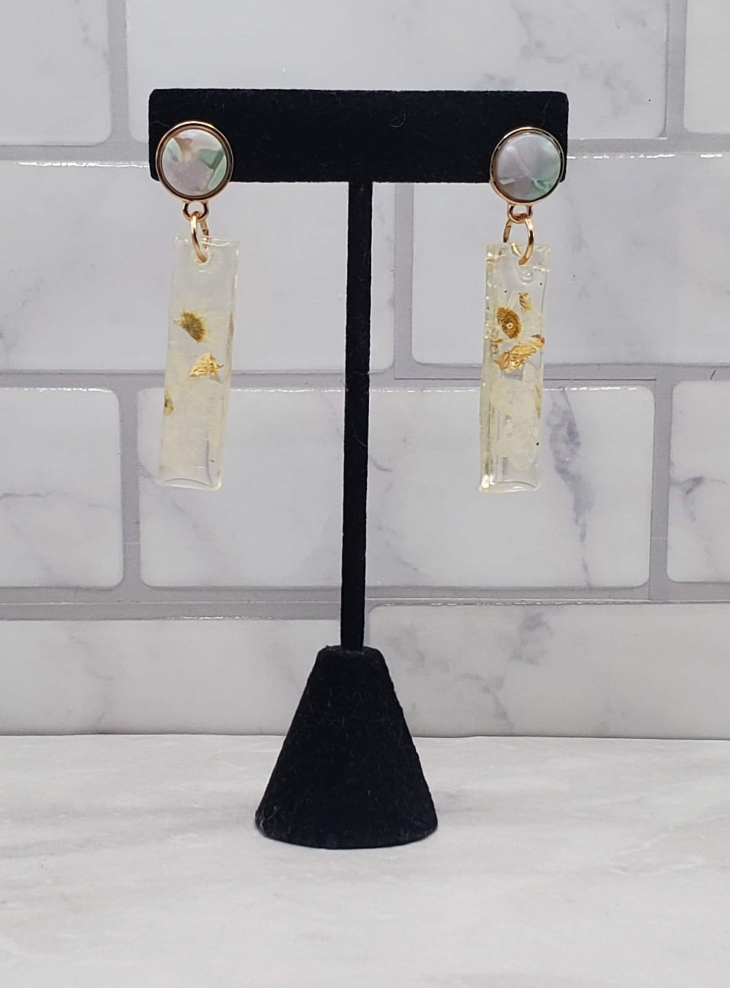 White floral bar earrings | pressed flower resin earrings on black earring display | Braceliss