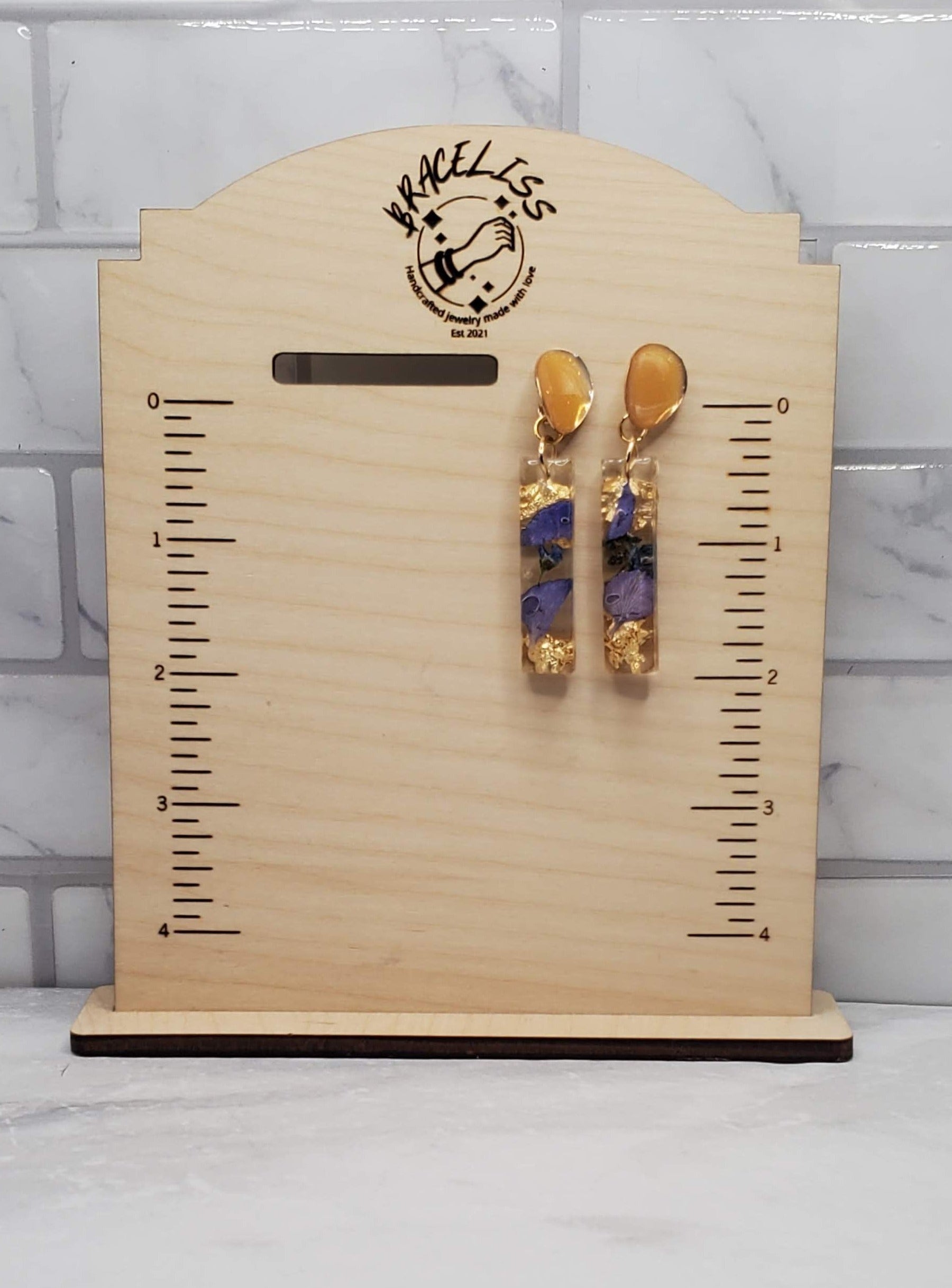 Purple floral bar earrings | pressed flower resin earrings on measuring display | braceliss