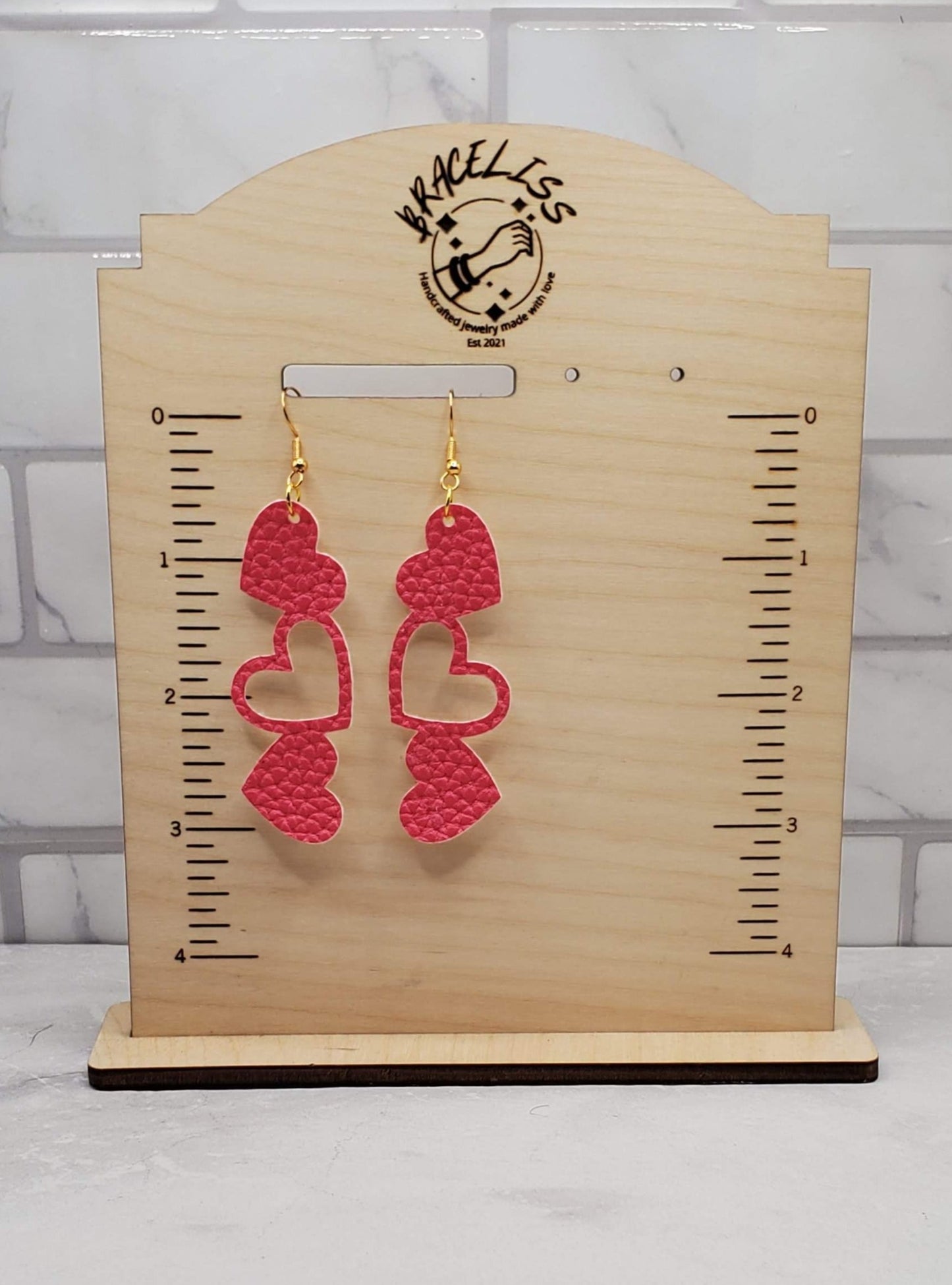 stacked heart earrings - dark pink faux leather drop earrings on measuring display - braceliss